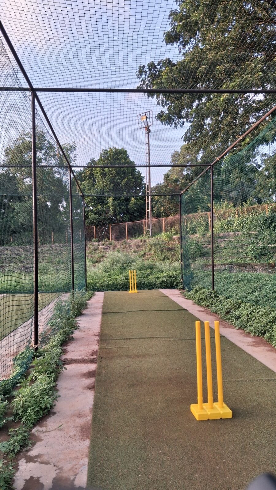 Straight cricket net view with both stump sets aligned down the pitch.
